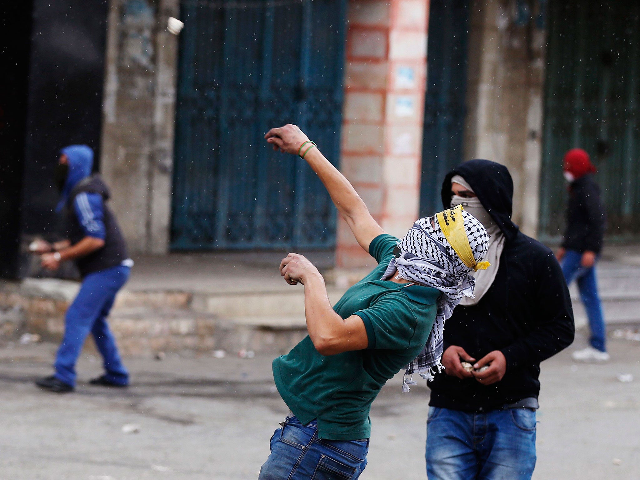 A Palestinian protester throws a stone at Israeli troops during clashes in the West Bank town of Abu Dis near Jerusalem