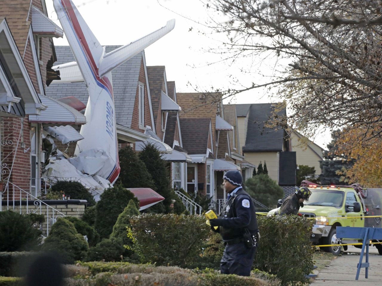 Police and fire officials walk near a small twin-engine cargo plane that crashed into a home on Chicago's southwest side