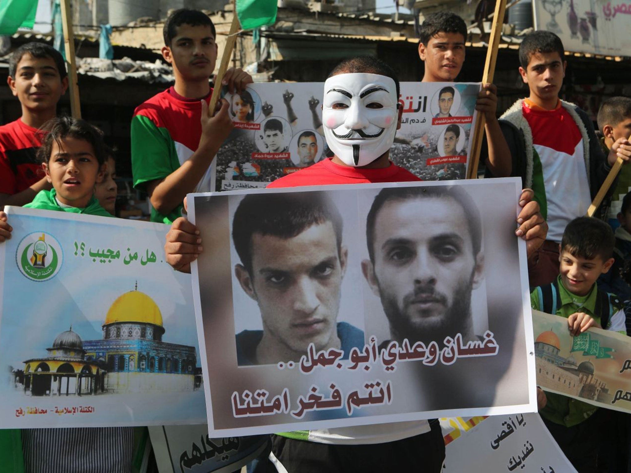 A masked Palestinian celebrates the attack on the Jerusalem synagogue holding a poster of the attackers,Ghassan and Uday Abu Jamal, during a rally in Rafah in the southern Gaza Strip