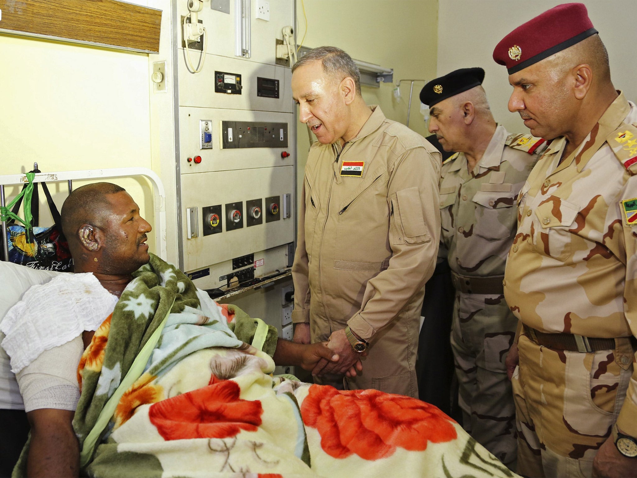 Iraqi defence minister Khaled al-Obeidi meets a soldier wounded in Baiji fighting
