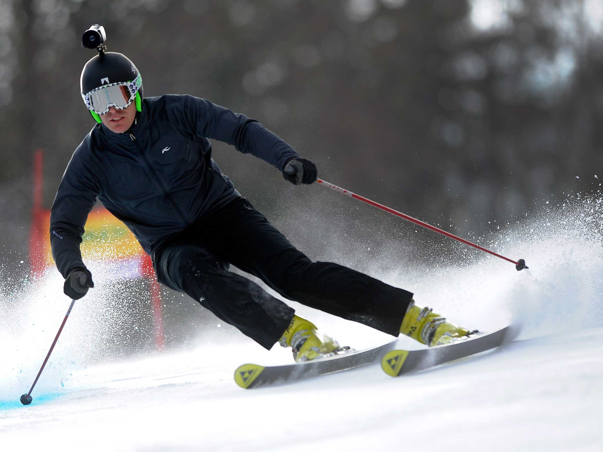 A cameraman skis down a slope with a helmet mounted camera
