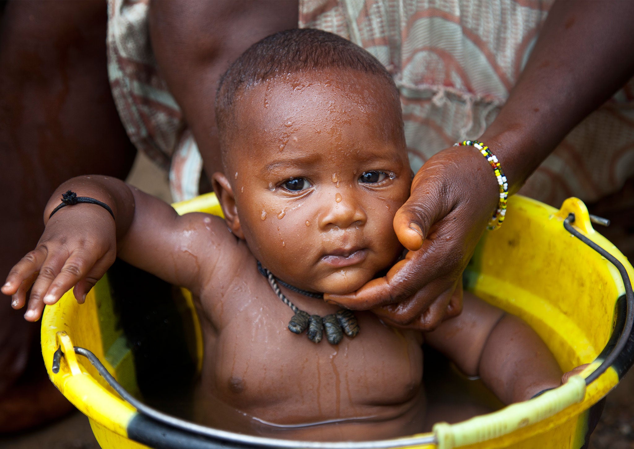 A baby is washed in safe clean water, in the village of Fayama, Sierra Leone, May 2013.