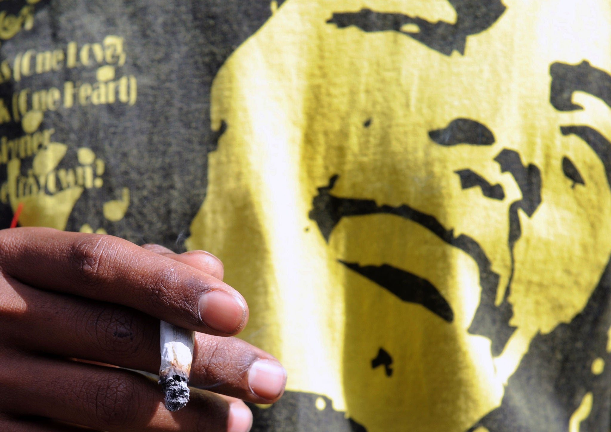 A man smokes a joint while wearing a Bob Marley T-shirt