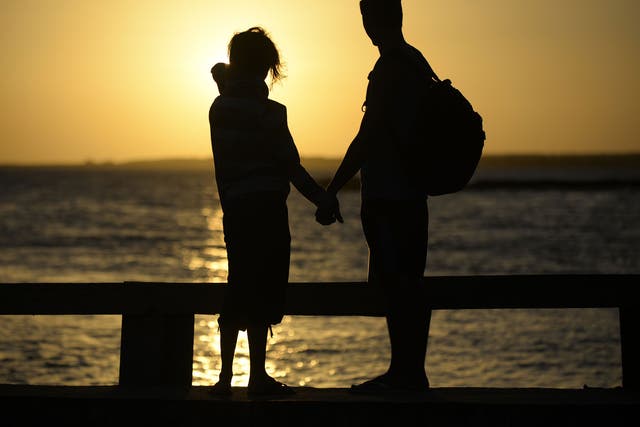 A couple hold hands near the shore 