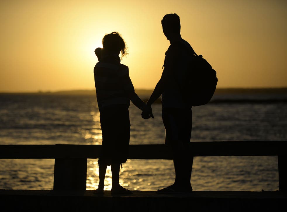 A couple hold hands near the shore 