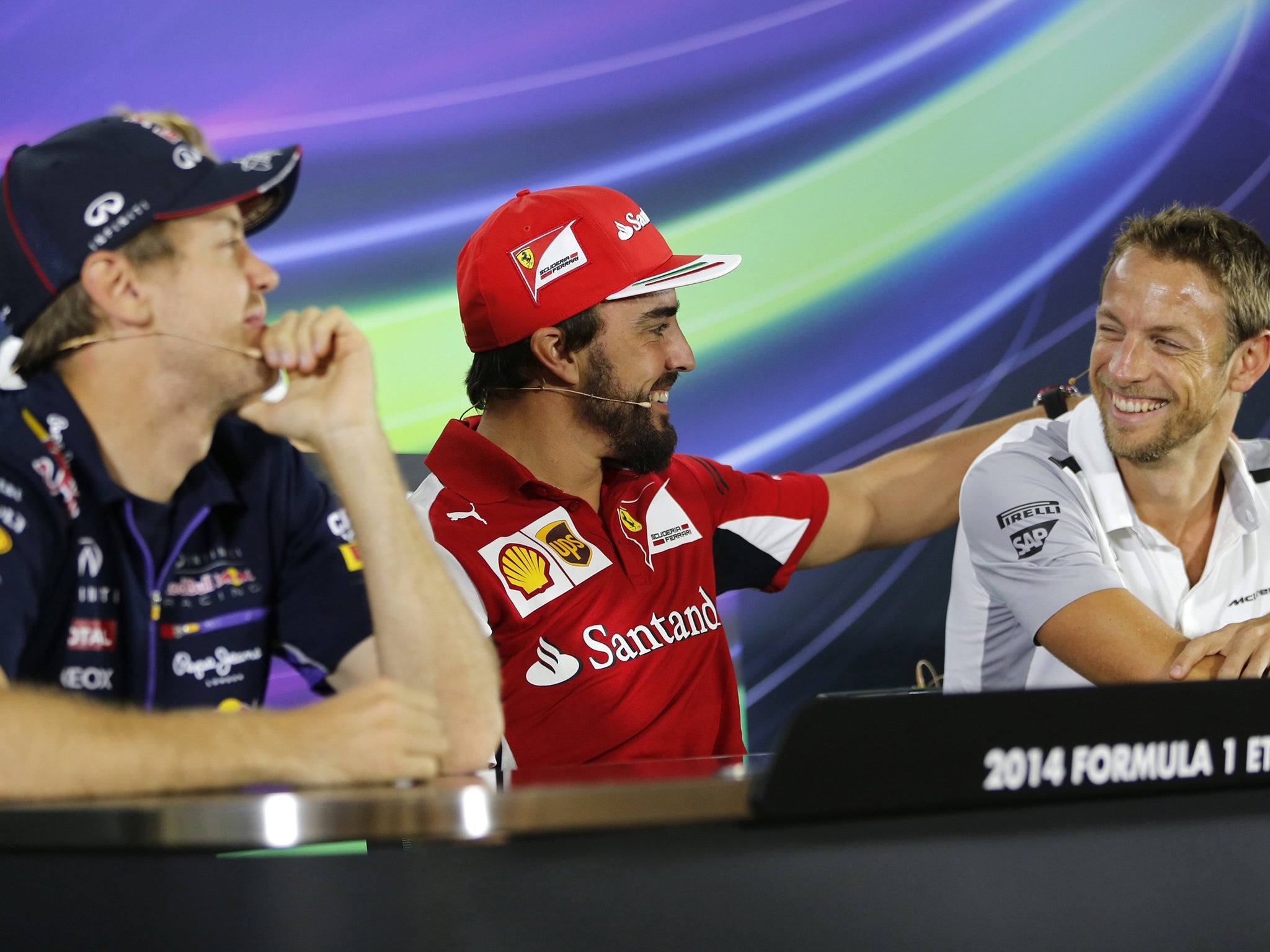 Sebastian Vettel (left) watches as Fernando Alonso (centre) shares a light-hearted moment with Jenson Button during a news conference at the Yas Marina circuit yesterday