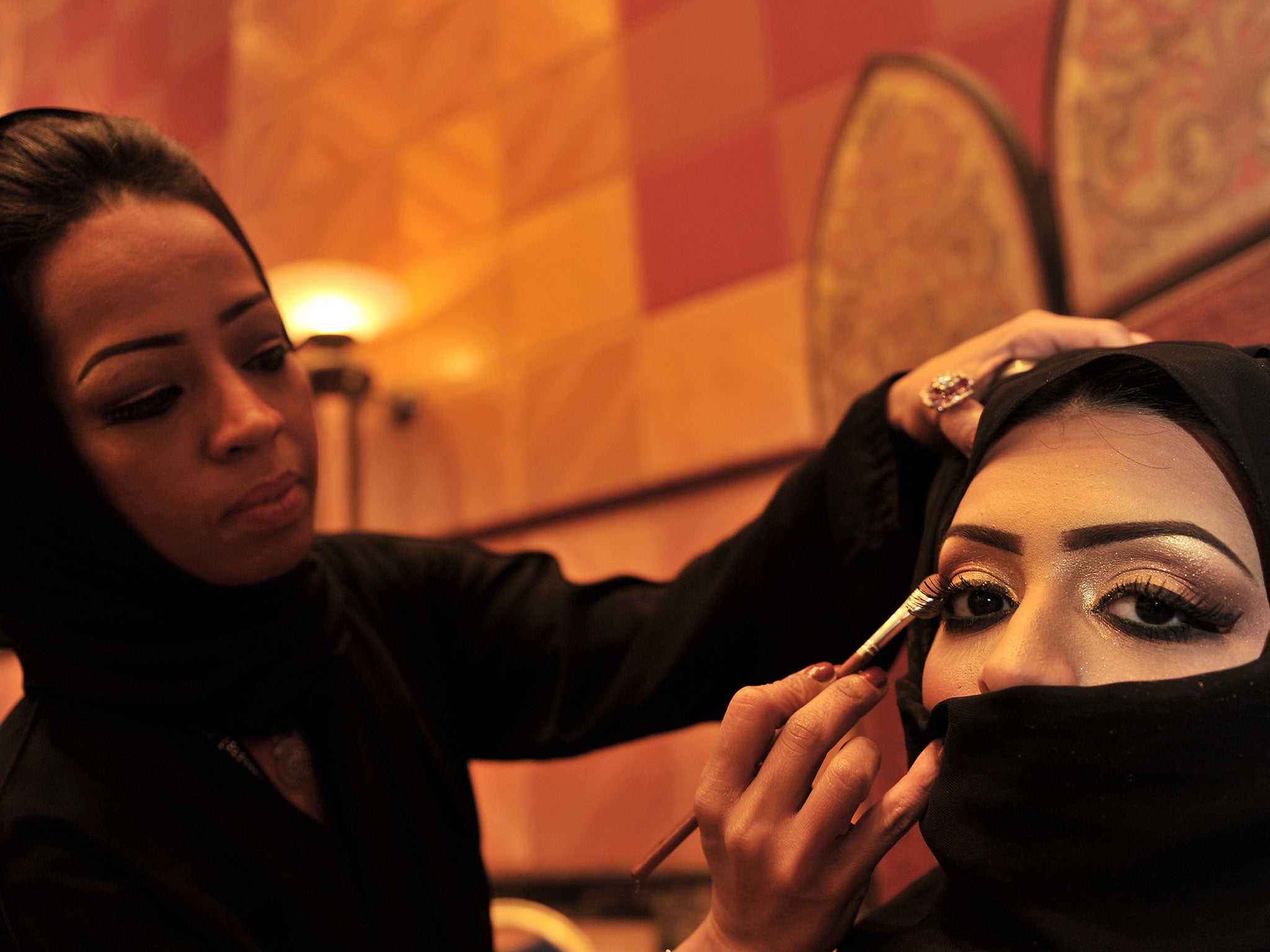 A Saudi woman applies makeup on a model during a beauty and style competition on the sidelines of the 2010 Cosmetic Expo