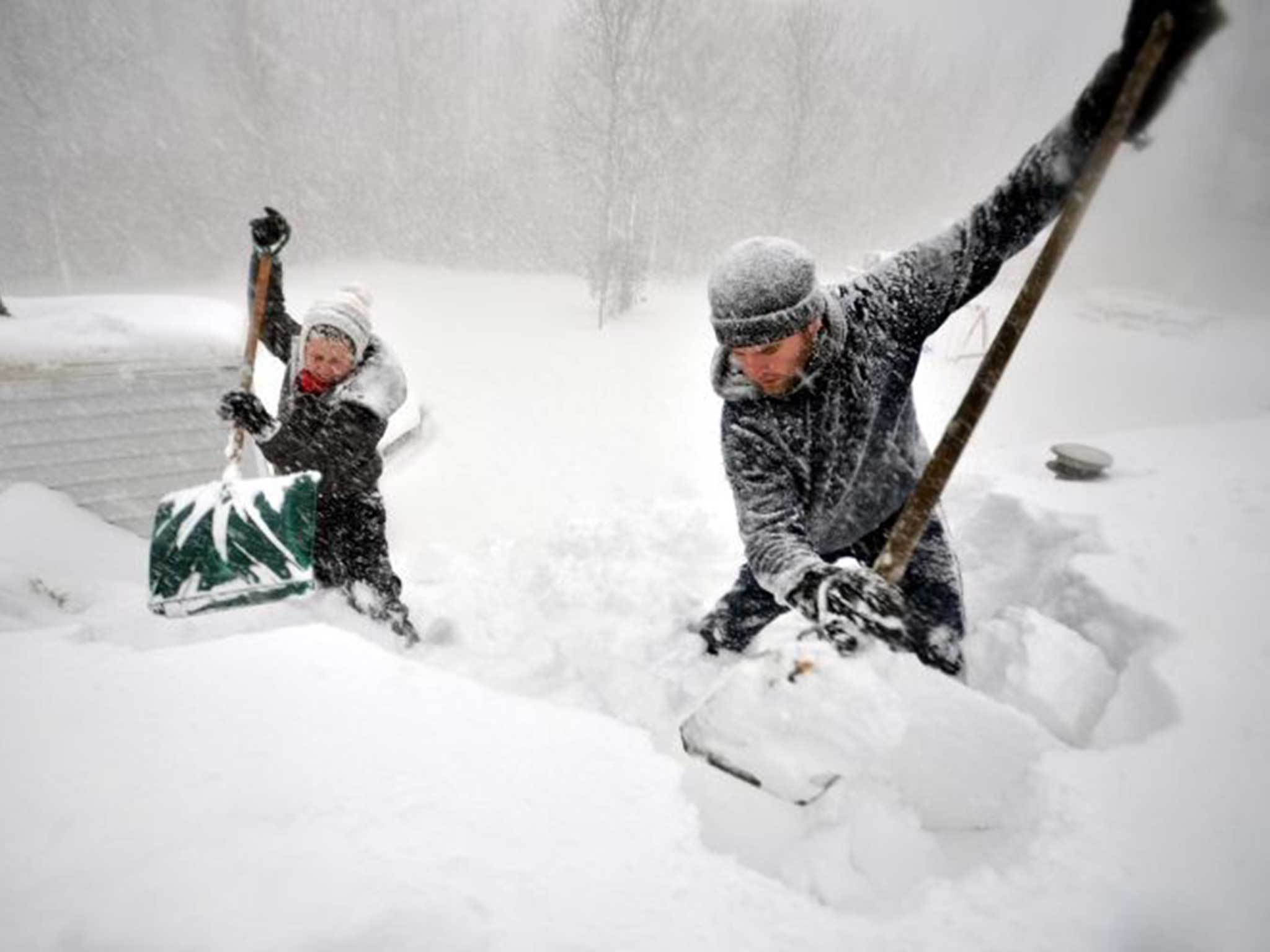 Two Buffalo residents attempt to remove some of the snow on their roof