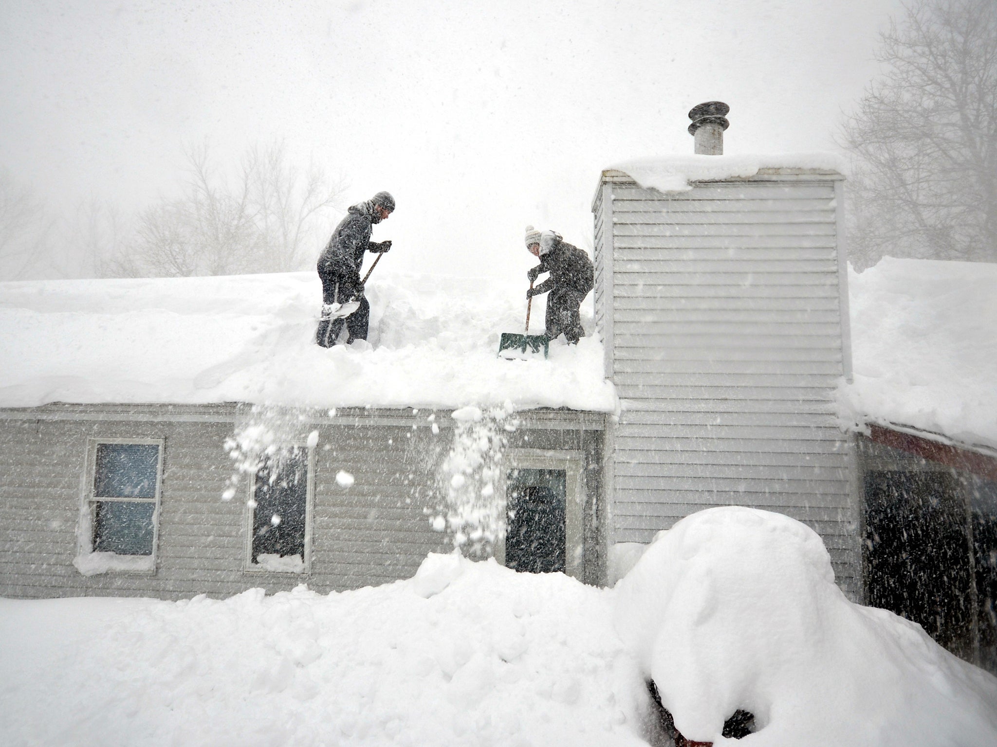 Tami Normile and Richard Brooks attempt to remove some of the five feet of snow from a roof top on November 20, 2014 in the Lakeview neighborhood of Buffalo, New York.