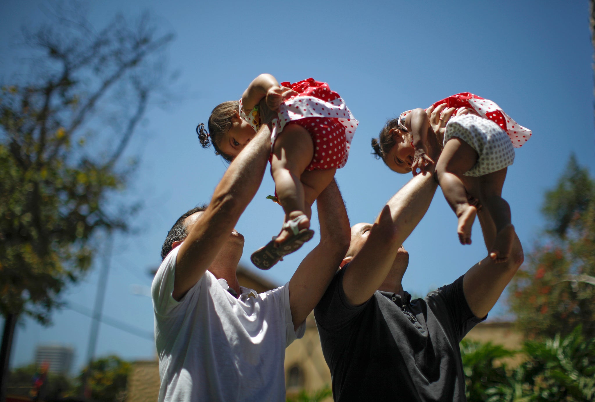Jason Howe, 48, and Adrian Perez (L), 48, who were married in Spain, and again in California, hold their one-year-old twin daughters Clara (R) and Olivia at a playground in West Hollywood.