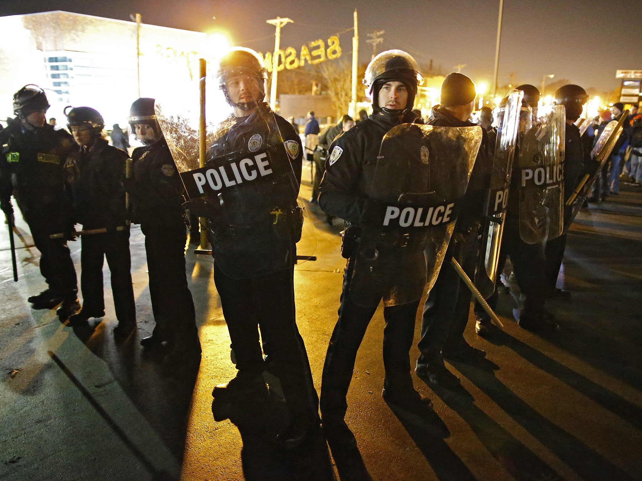 Police rush in to break up protesters outside the Ferguson Police Station in Ferguson, Missouri