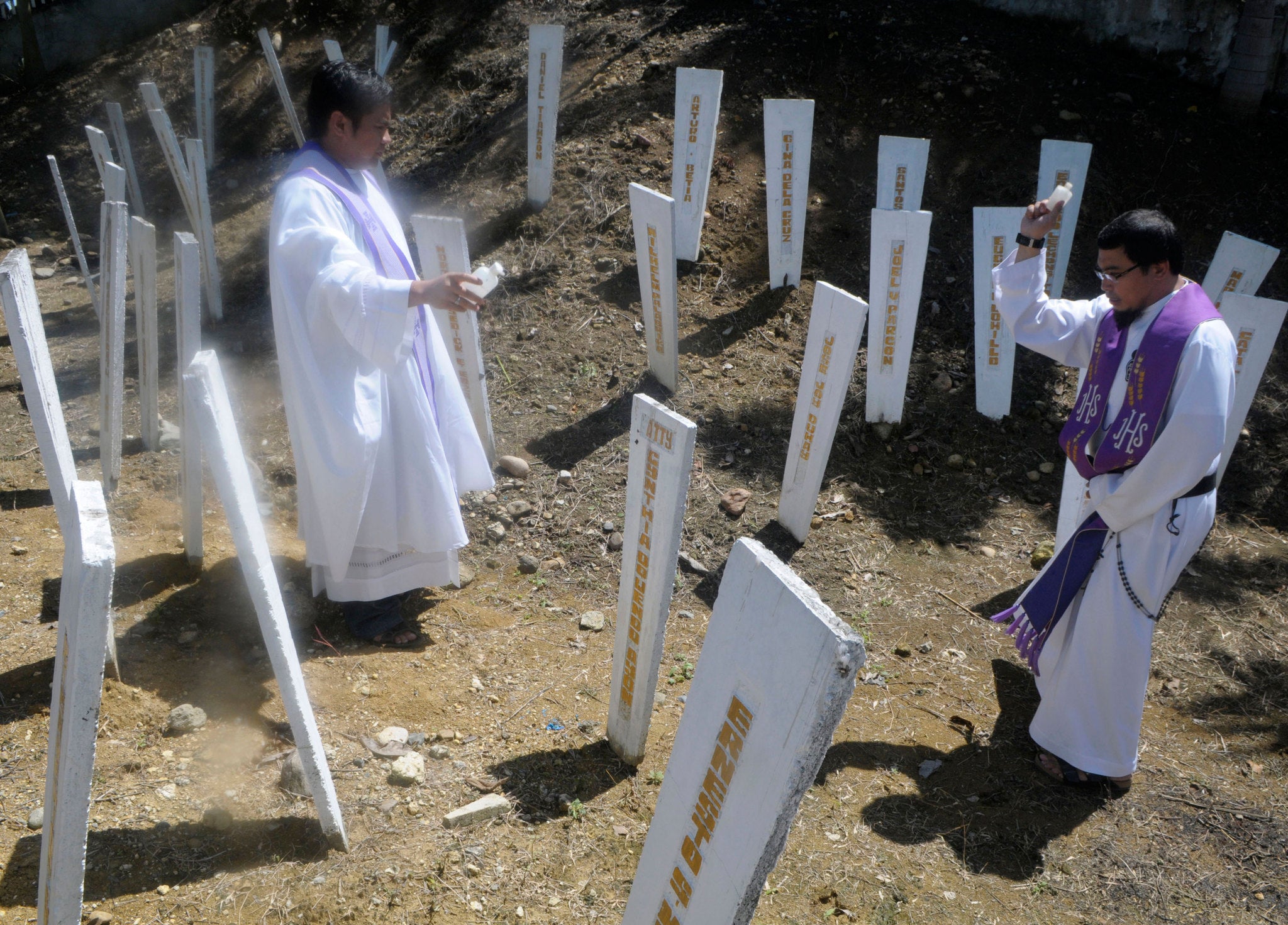 Roman Catholic priests bless the wooden markers at the site where 58 people, 32 of them journalists, were massacred at a remote village in Ampatuan township, Maguindanao province in southern Philippines.