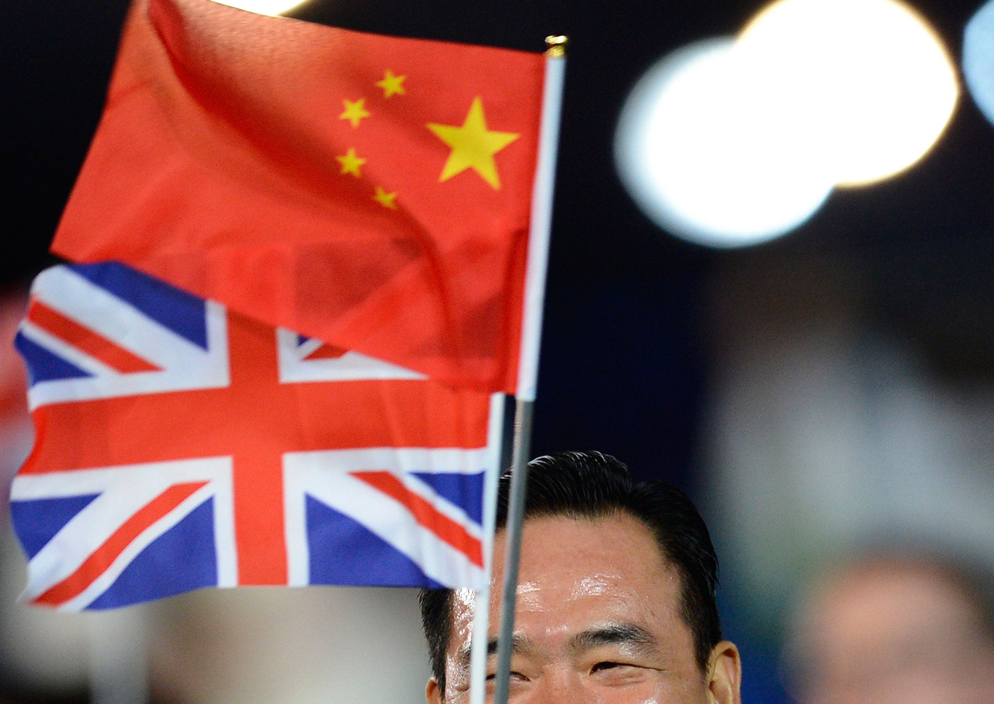 A member of the China's delegation holds a Chinese and a Union Jack flags as he parades during the opening ceremony of the London 2012 Olympic Games
