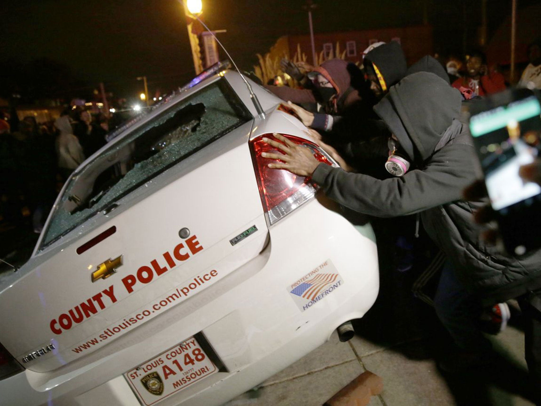 A group of protesters vandalize a police vehicle