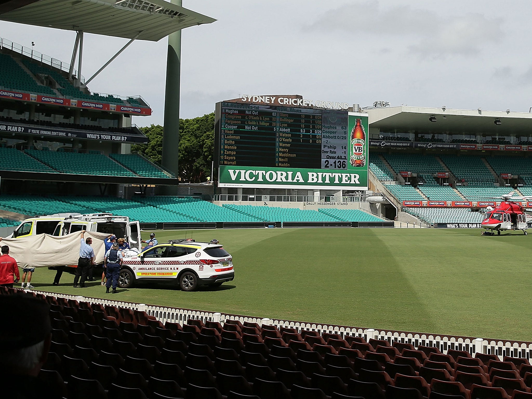 Hughes is escorted by stretcher to an air ambulance that has landed on the SCG pitch