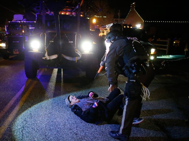 Police in riot gear tangle with a woman in front of emergency vehicles in Ferguson Missouri