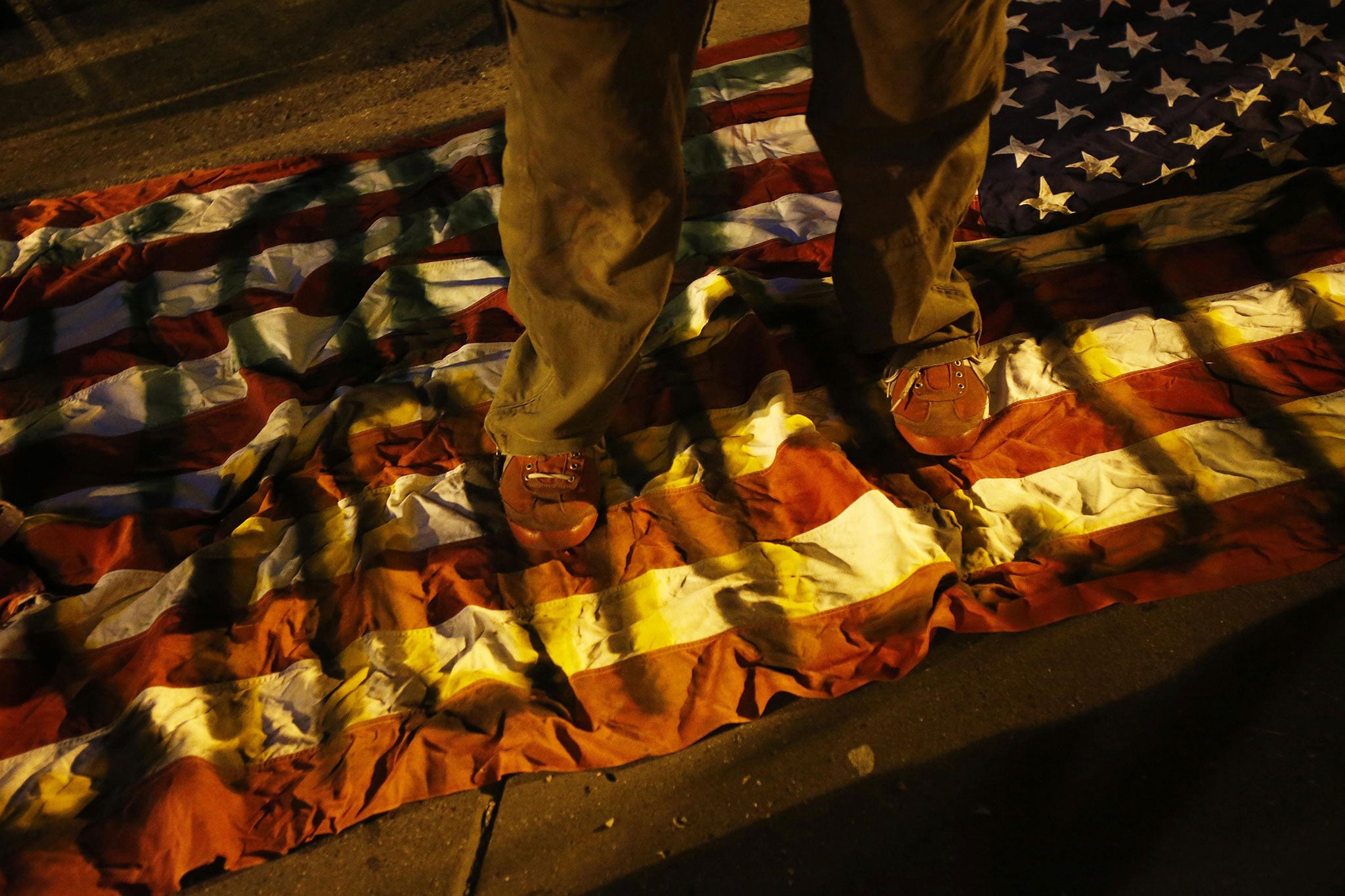A demonstrator steps on a graffiti-sprayed American flag during a protest in Oakland, California following the grand jury decision in Ferguson