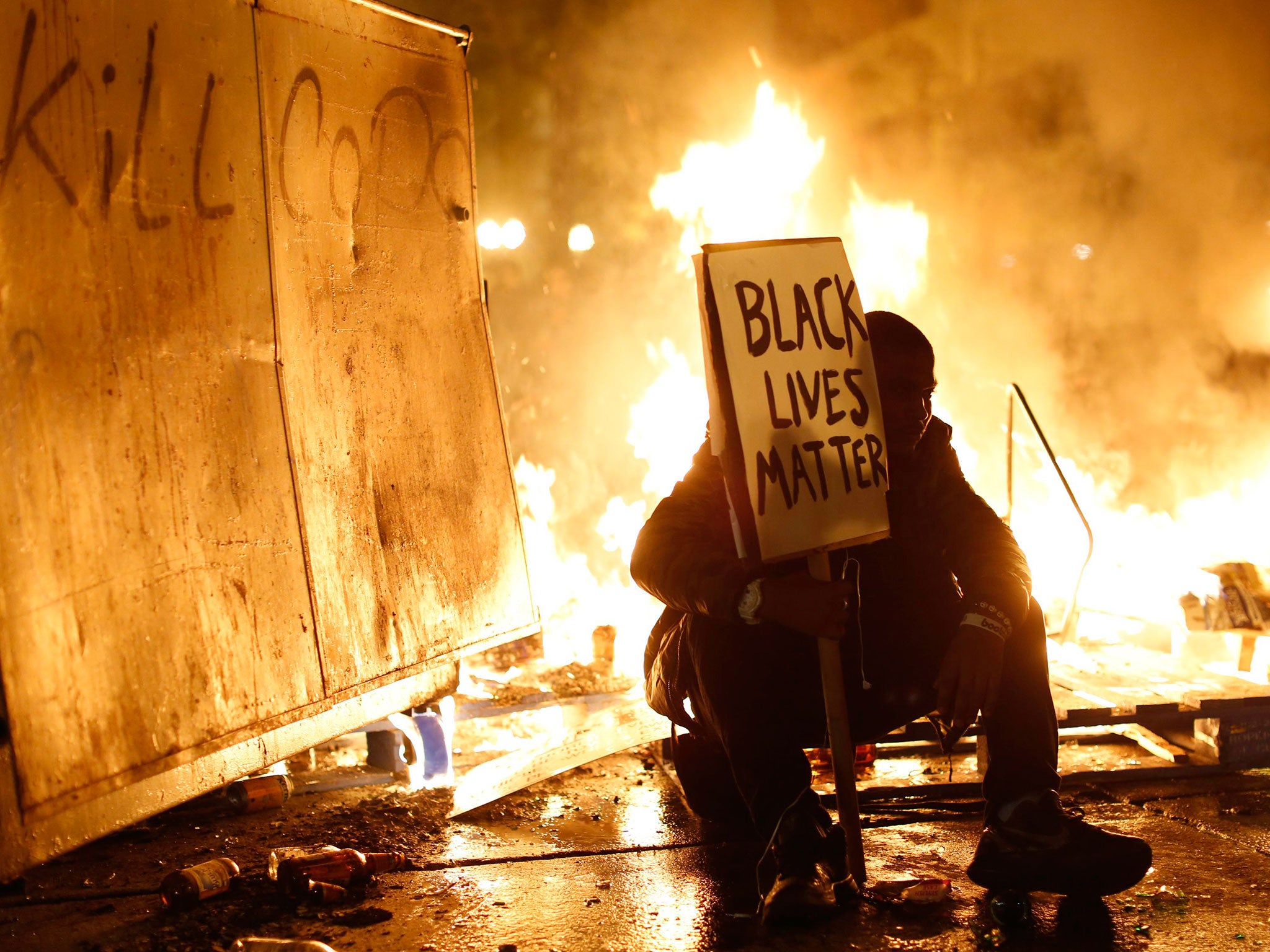 A demonstrator sits in front of a street fire in Ferguson