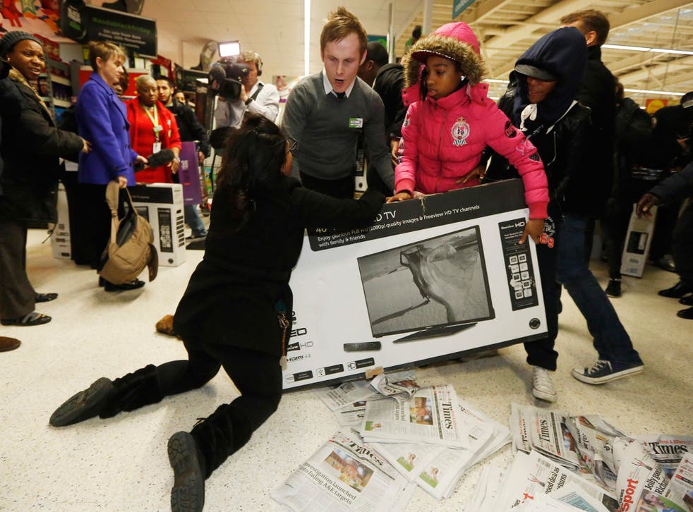 A member of staff intervenes as shoppers wrestle over a television