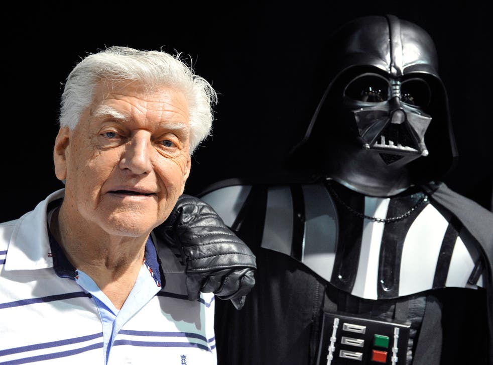 David Prowse poses for a photo with a fan dressed as Darth Vader