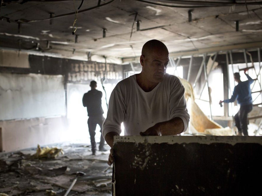Workers go through a burned classroom after it was set on fire by suspected arsonists at the Max Rayne Hand in Hand School in Jerusalem on the night of 29 November 2014
