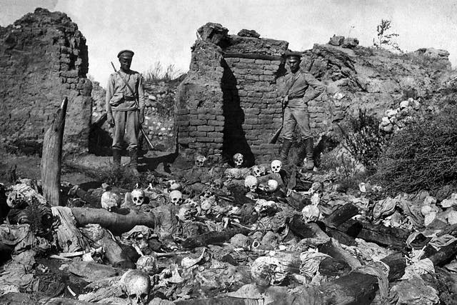 Soldiers standing over skulls of victims from the Armenian village of Sheyxalan in 1915, believed to be victims of the mass killing