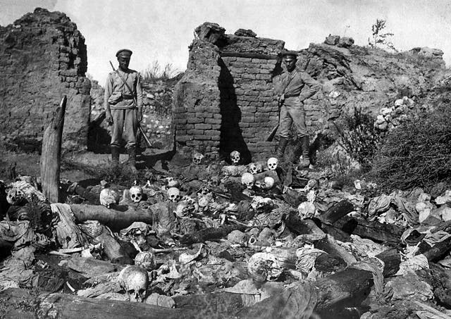 Soldiers standing over skulls of victims from the Armenian village of Sheyxalan in 1915, believed to be victims of the mass killing