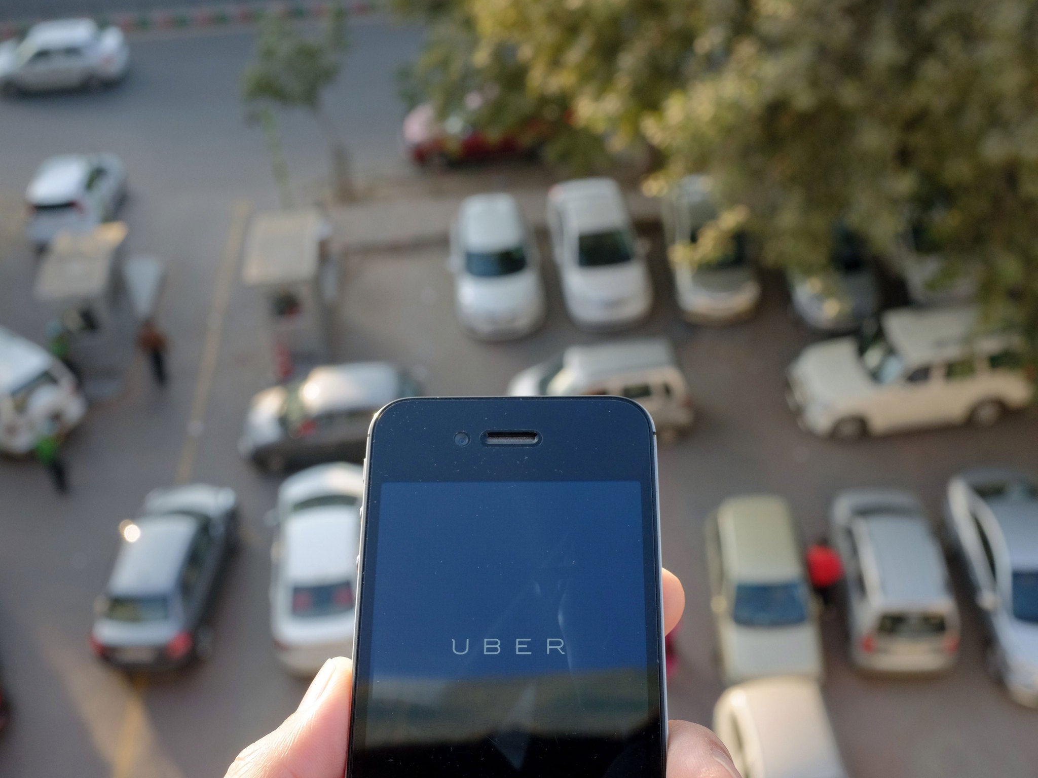 The Uber smartphone app, used to book taxis using its service, is pictured over a parking lot in the Indian capital New Delhi on December 7, 2014