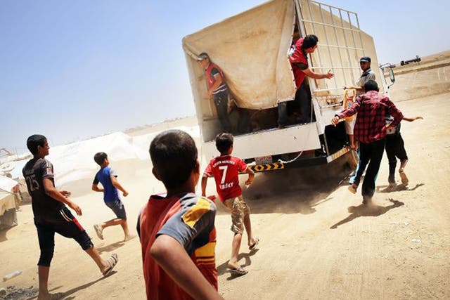 Iraqis at the Khazair camp for those caught up in the fighting around Mosul chase a Red Crescent truck delivering supplies 