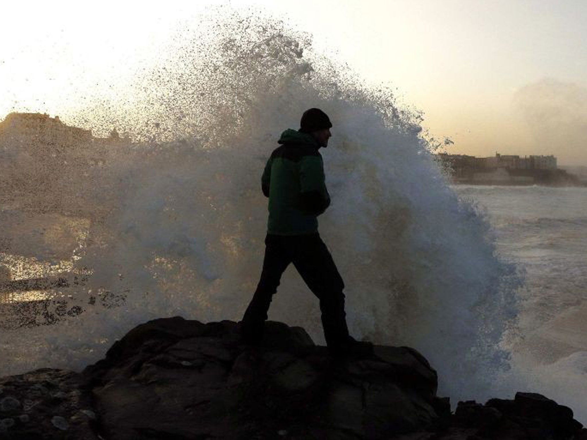 A man watches as waves crash into a cliff at Portstewart in northern Ireland 