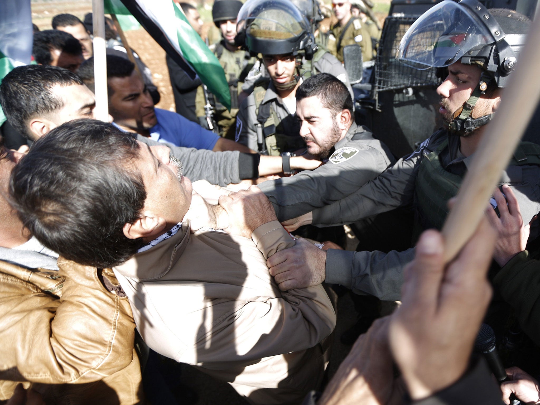 An Israeli border guard grabs Palestinian official Ziad Abu Ein (L) during the demonstration in the village of Turmus Aya near Ramallah, on December 10, 2014