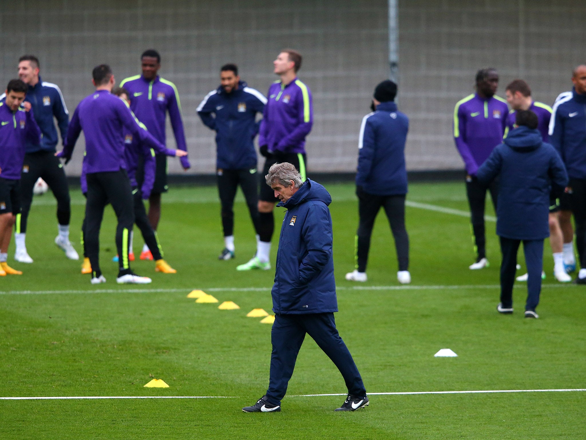 Manuel Pellegrini the manager of Manchester City walks past his players during a training session.