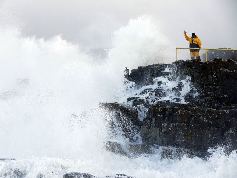 A man signals as waves crash against the shore at Portstewart in northern Ireland