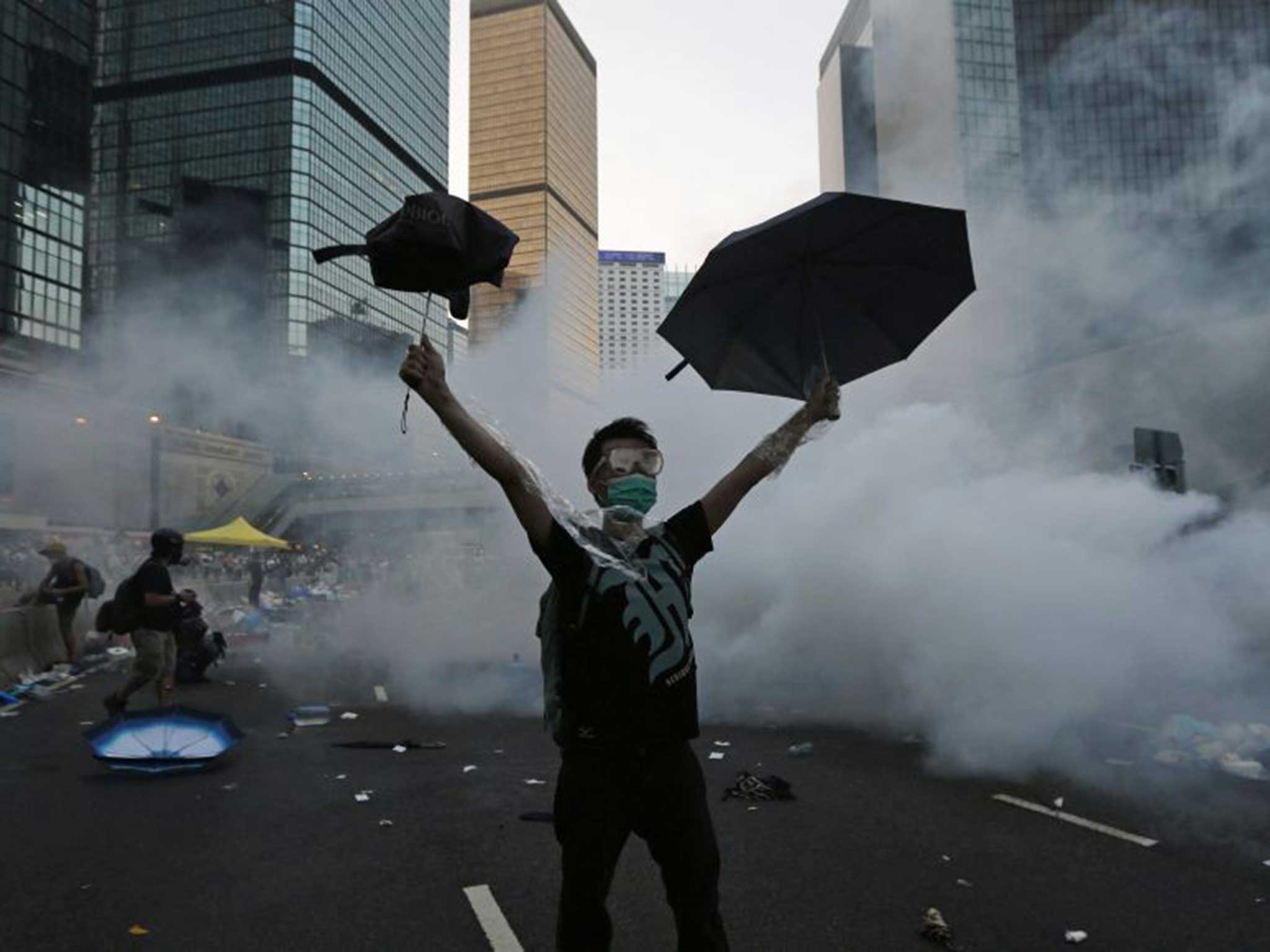 A Hong Kong protester raises his umbrellas in front of tear gas in September