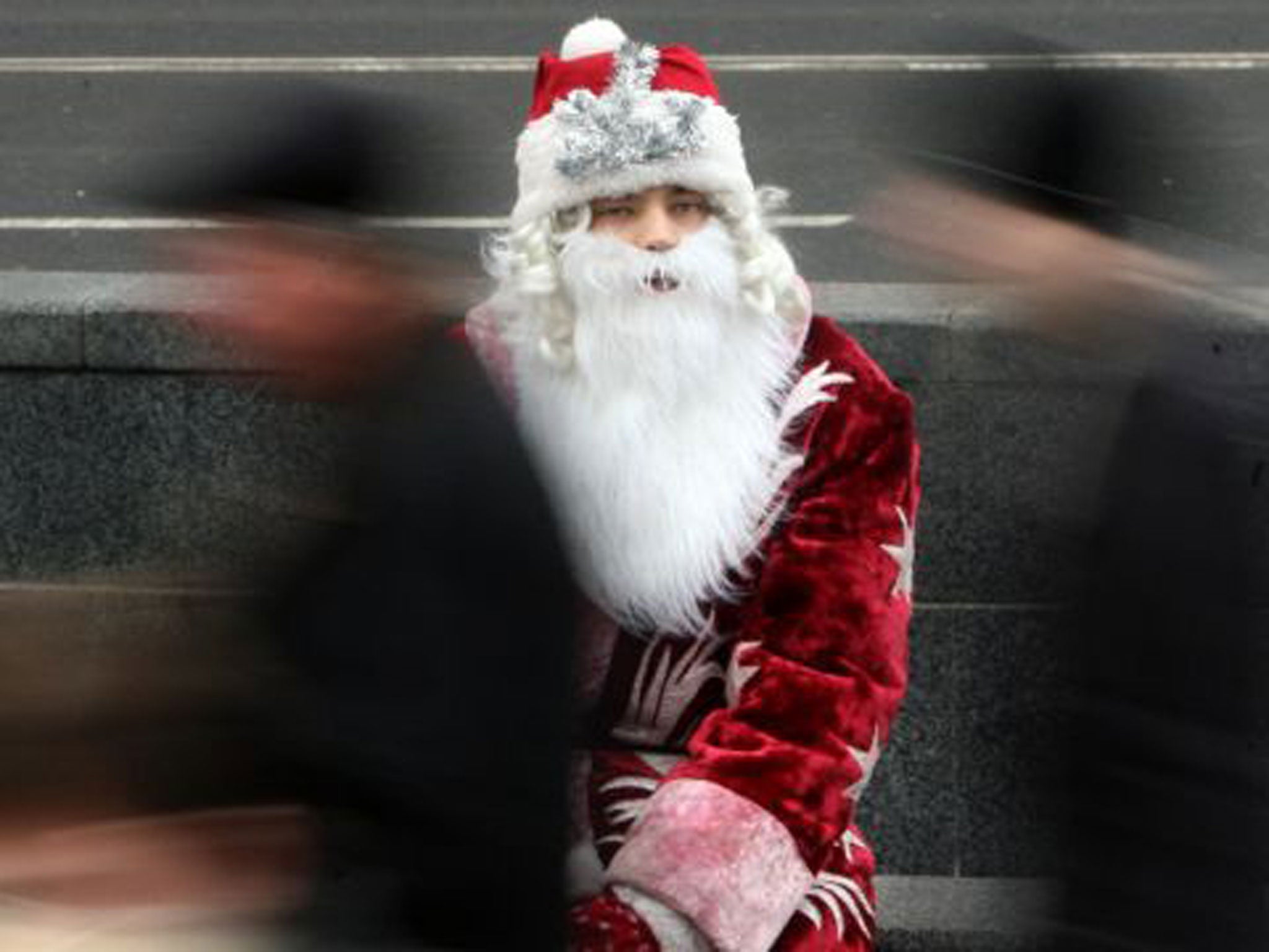 People pass Father Frost as he takes a break during Orthodox Christmas' eve festival in Kiev