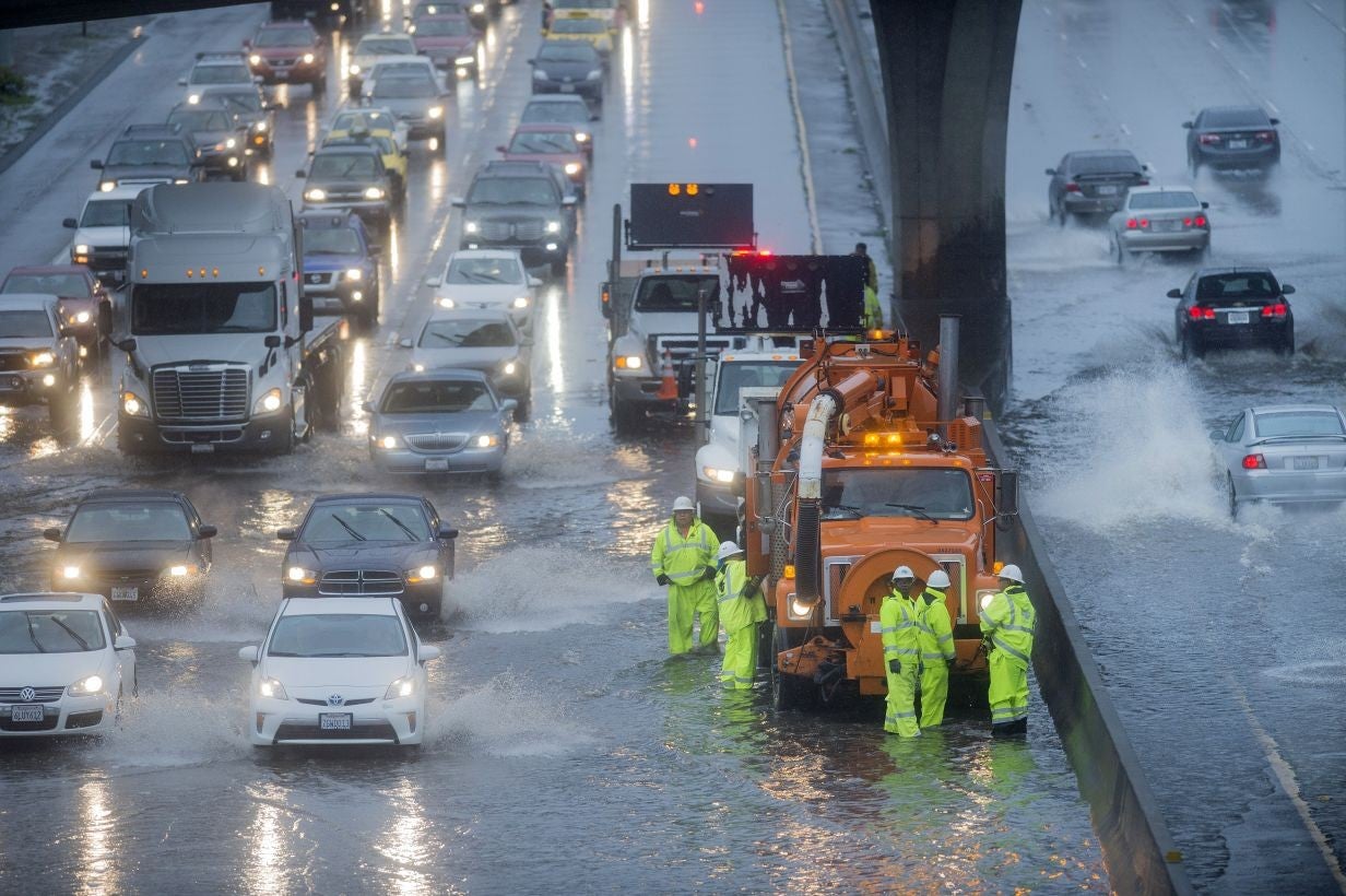 A crew of workers try to clear a flooded stretch of Highway 101 in South San Francisco