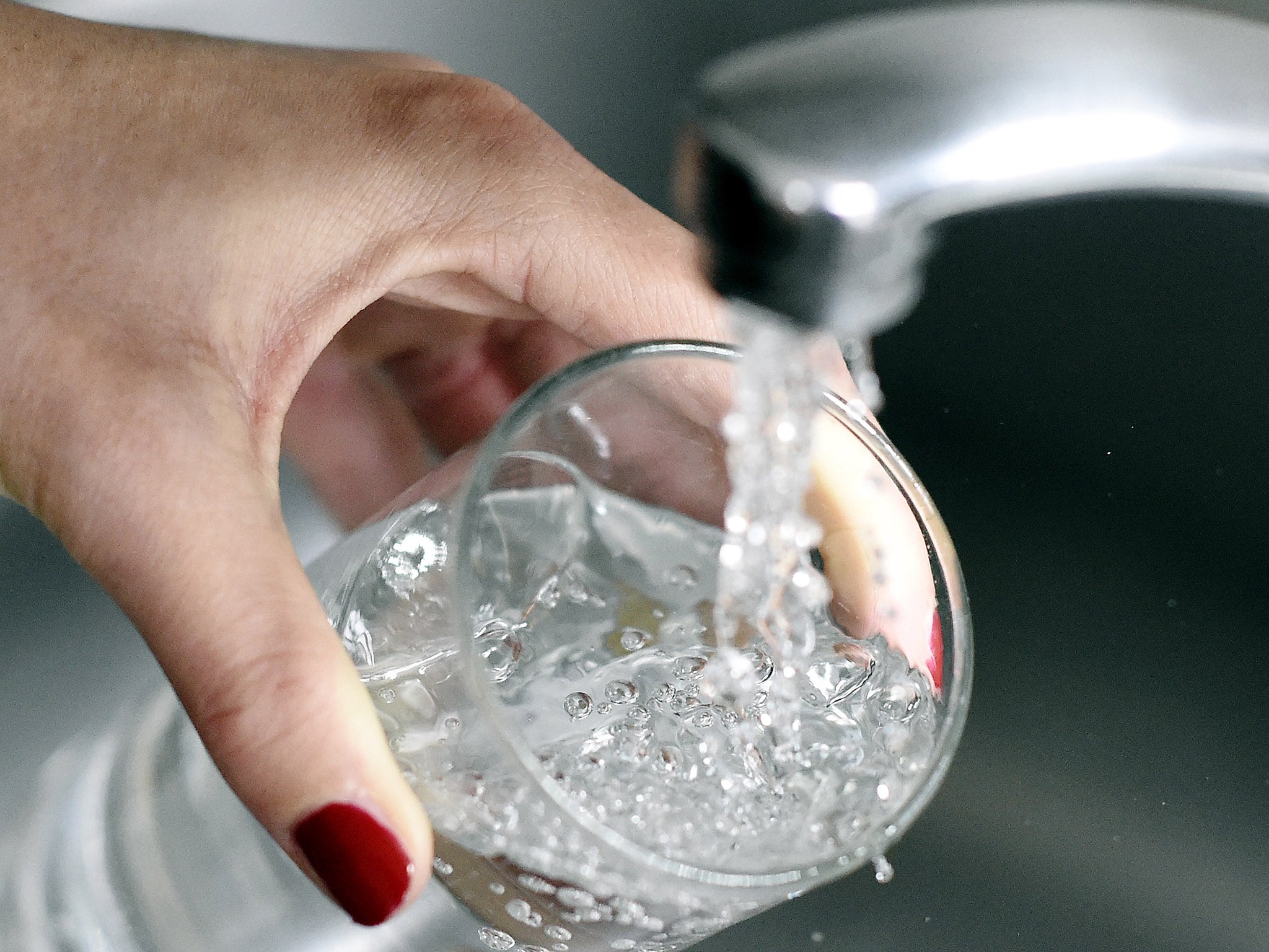 A woman fills up a glass with water.