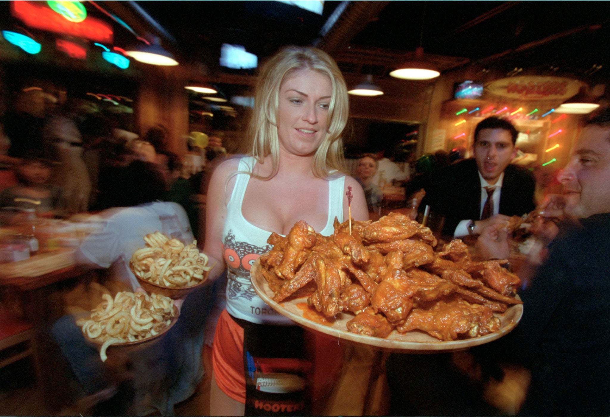 A waitress serves food to customers at Hooters