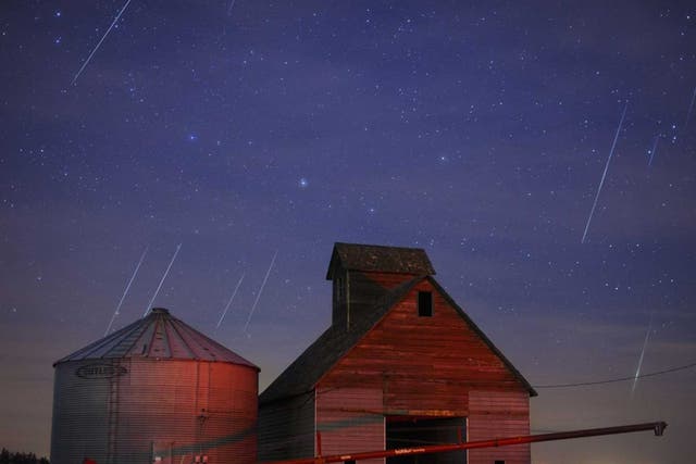 Geminid meteors streak across the sky behind a barn in western Iowa