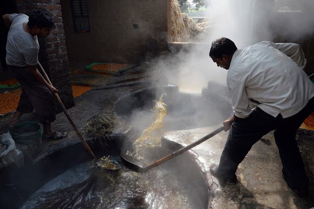 Indian workers boil sugarcane juice to make jaggery, a traditional cane sugar, at a jaggery plant in Muradnagar, Uttar Pradesh's Ghaziabad district