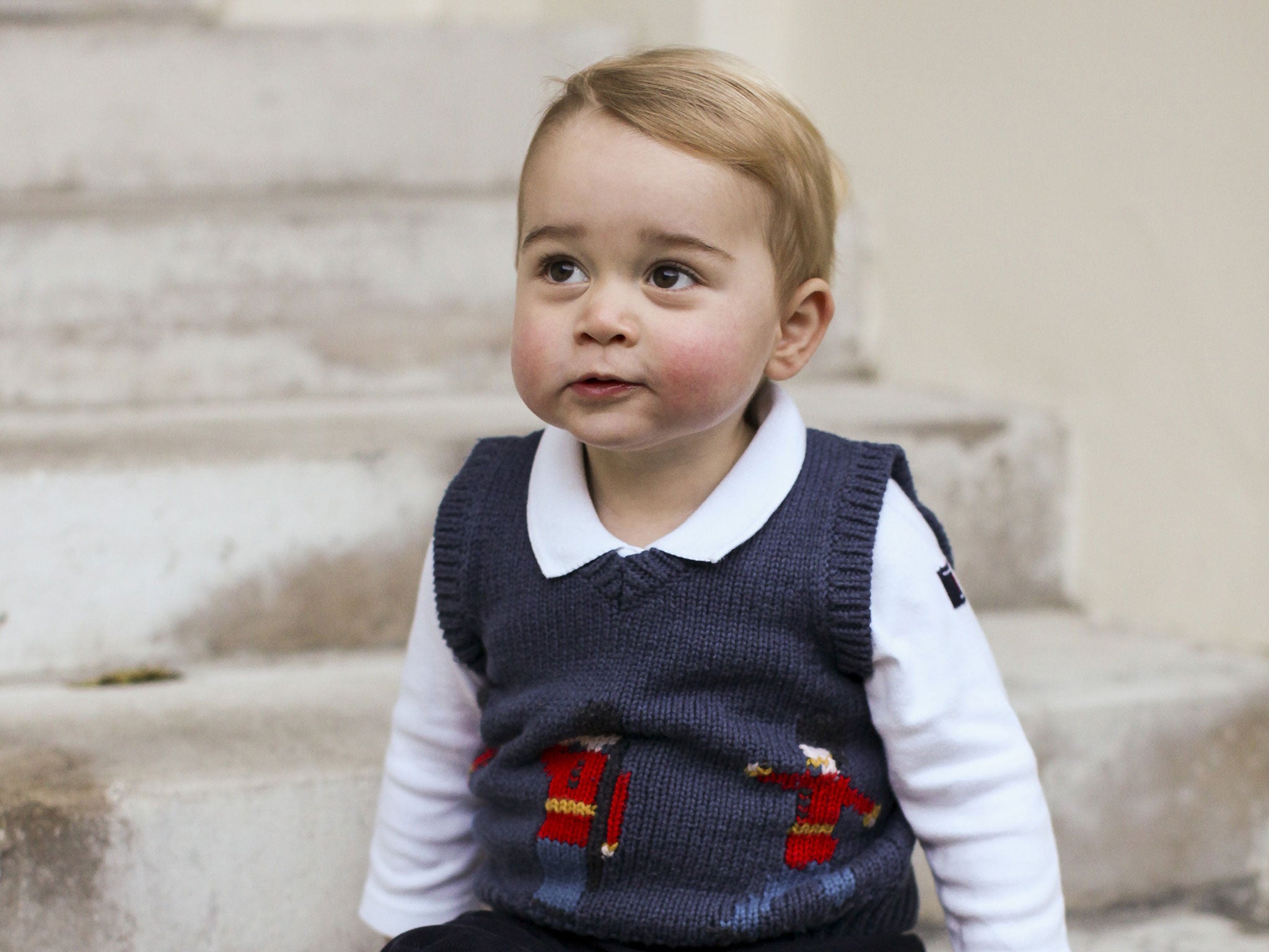 In this handout image of three released on December 13, 2014 by Kensington Palace, Prince George sits for his official Christmas picture in a courtyard