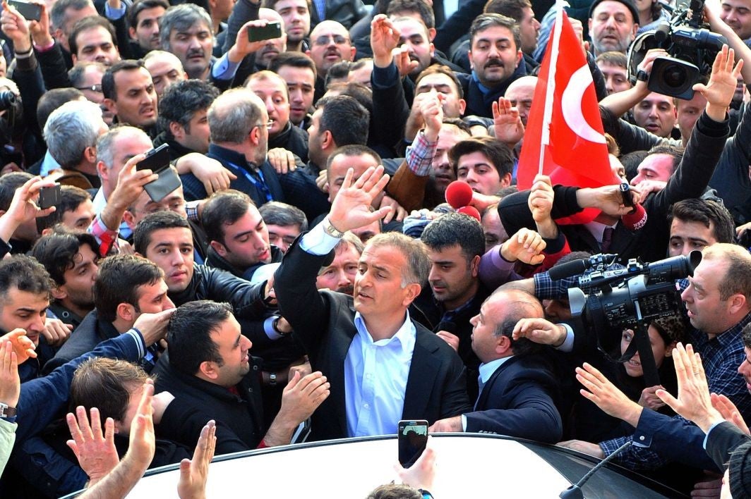 Staff members and supporters of the Zaman newspaper editor-in-chief Ekrem Dumanli shout slogans as he is arrested by plain clothes police and led towards a car.