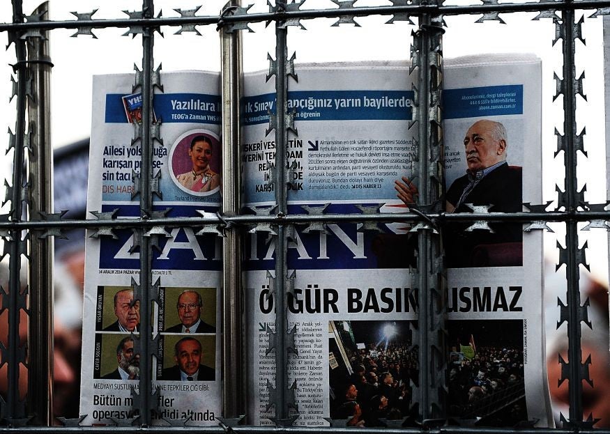 A supporter holds a copy of the Zaman newspaper behind a fence as police arrest its editor-in-chief in Istanbul.