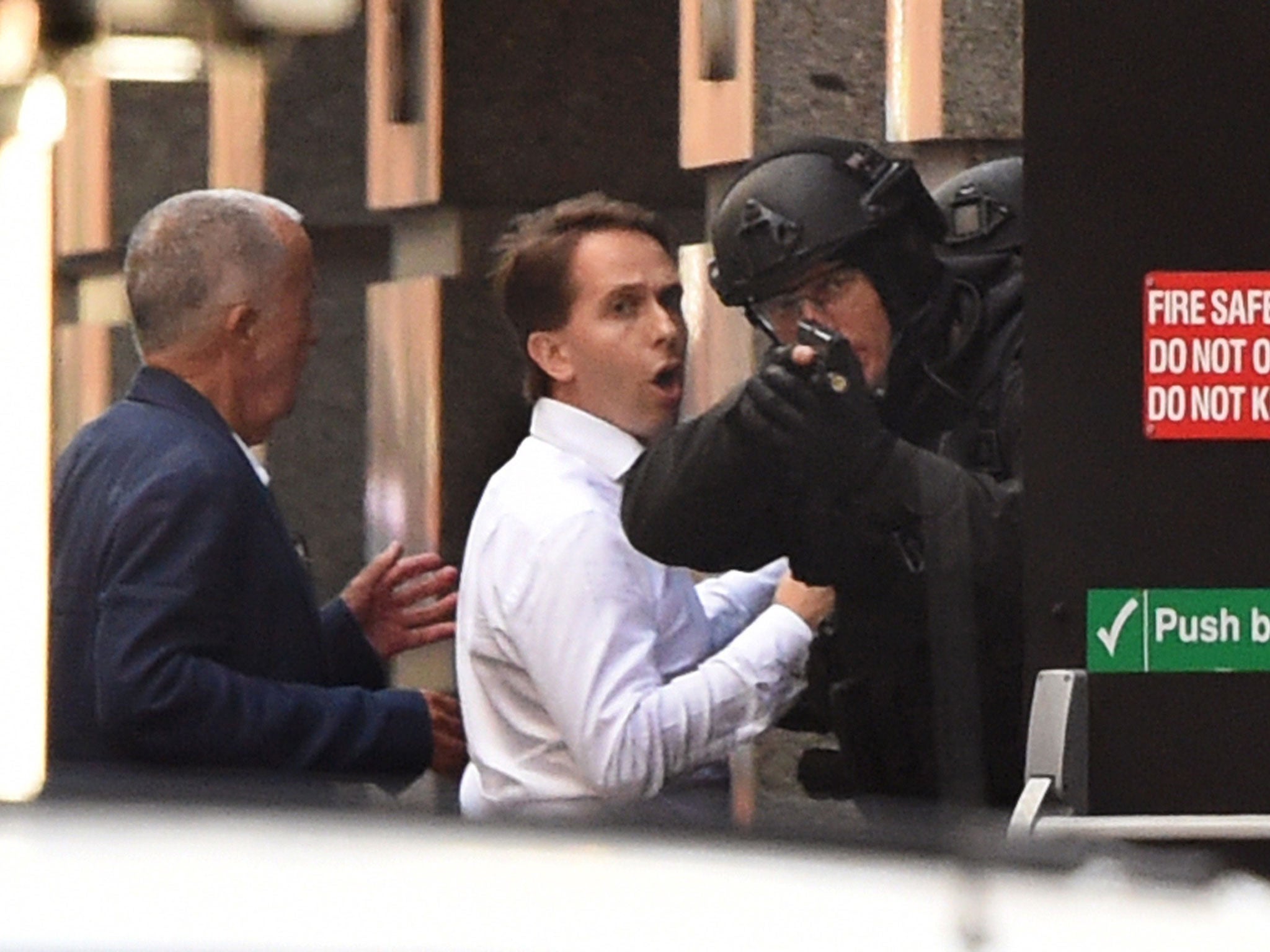 Two hostages run for cover behind a policeman during a hostage siege in a cafe in Sydney