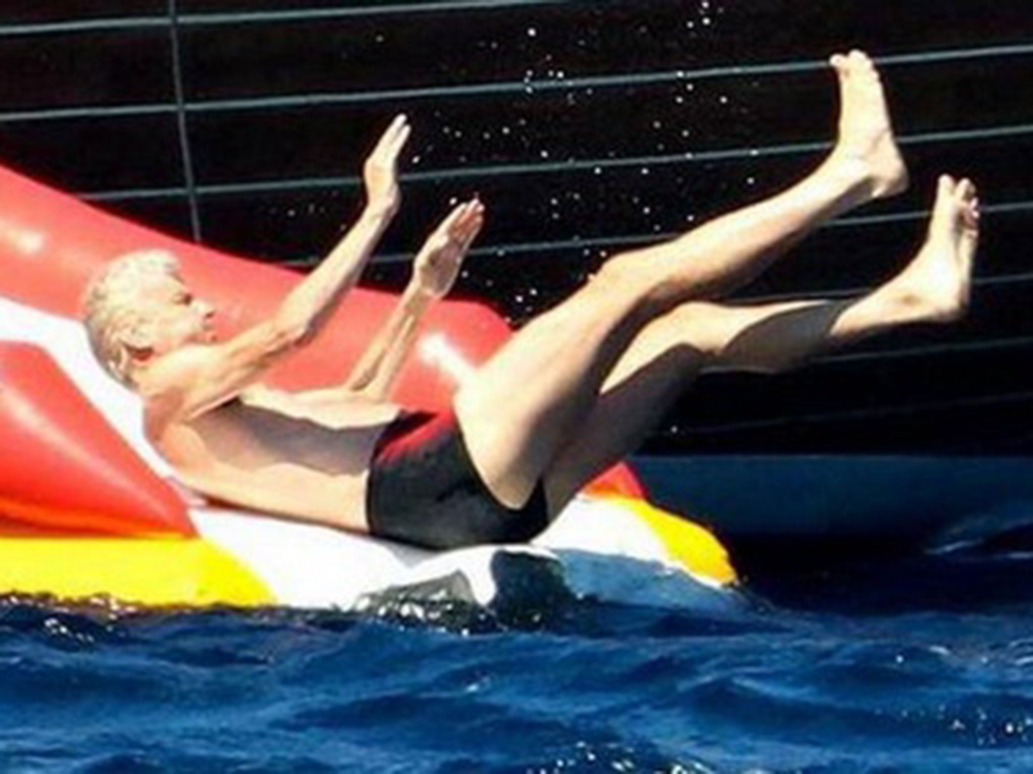 Arsene Wenger enjoys a water-slide during pre-season