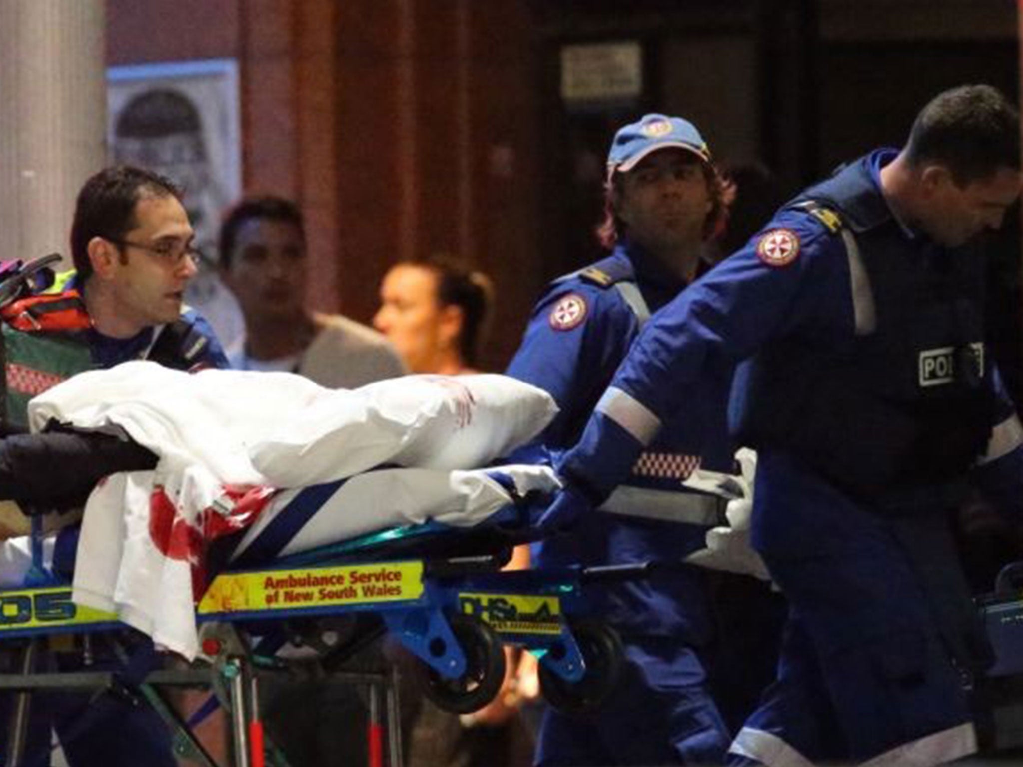 A blood-stained stretcher is wheeled to an ambulance after shots were fired during the cafe siege in Sydney