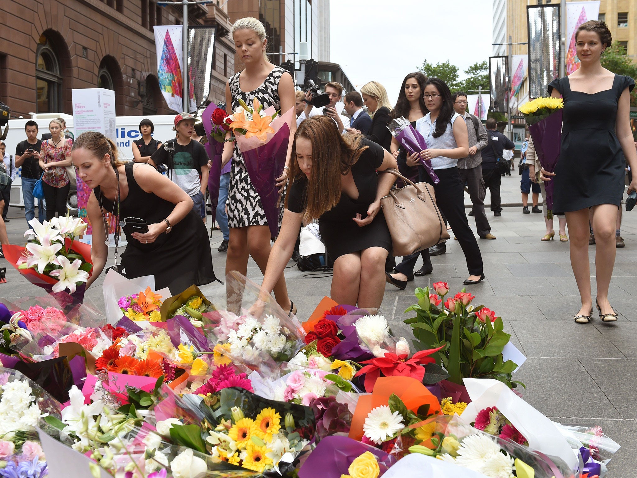 People lay flowers at a floral memorial at the scene of Sydney's siege
