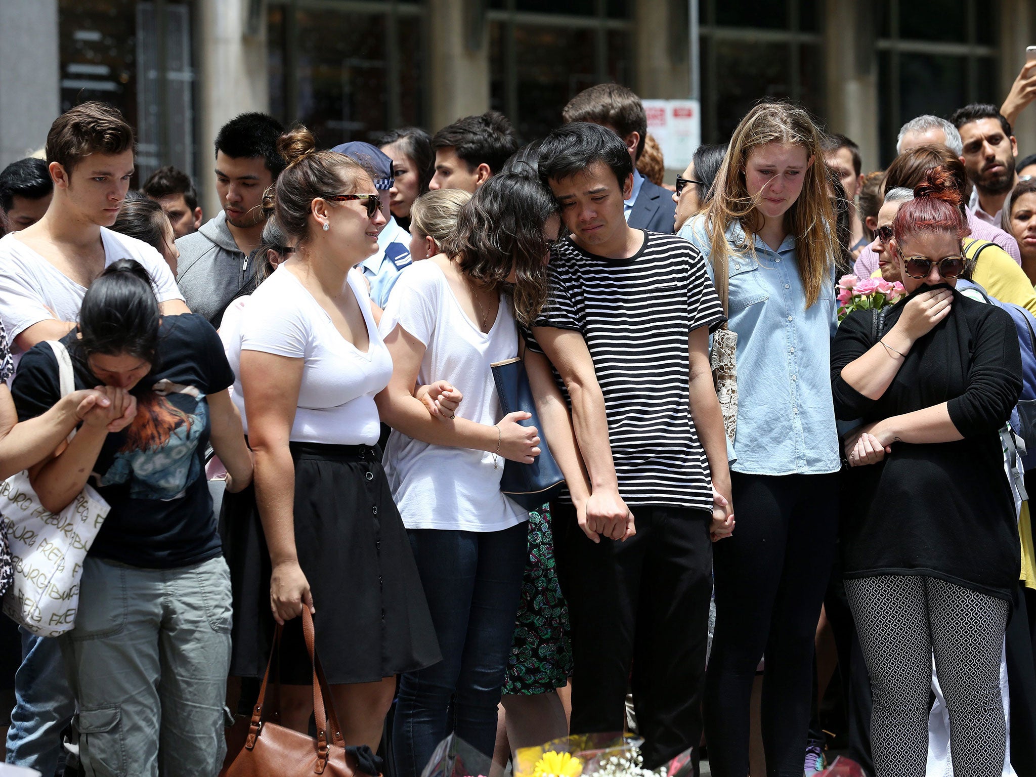 People join hands as they mourn near the Lindt chocolate cafe in Martin Place