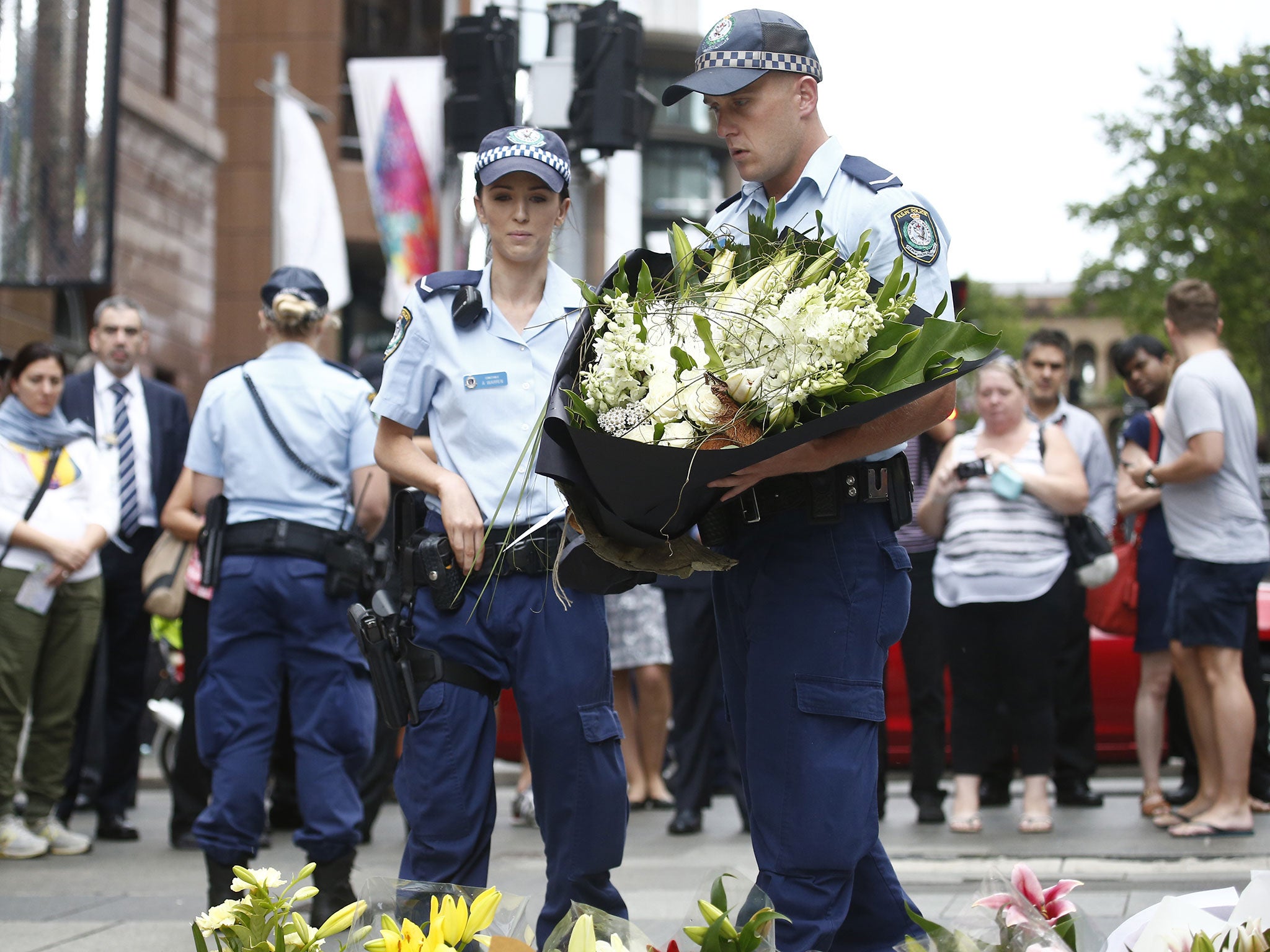 Police officers visit the floral memorial for victims Tori Johnson and Katrina Dawson at the scene of the Martin Place siege in the CBD in Sydney