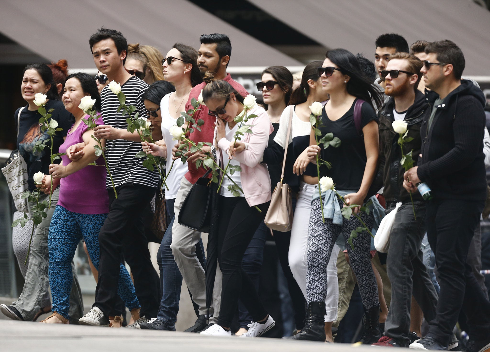 Grieving Lindt cafe workers lay flowers at the scene of the Martin Place siege, which claimed their manager Tori Johnson, in the CBD in Sydney